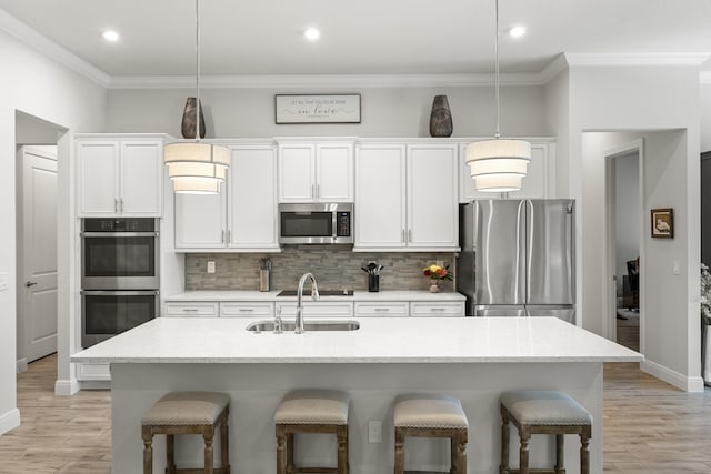 kitchen with an island with sink, pendant lighting, stainless steel appliances, and a breakfast bar