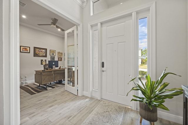 foyer featuring light wood-type flooring, crown molding, ceiling fan, and a wealth of natural light