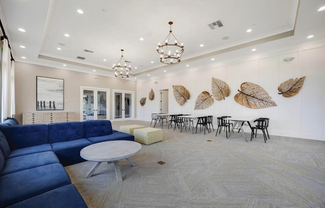 living room featuring a tray ceiling, an inviting chandelier, light colored carpet, and french doors