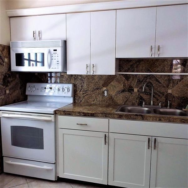 kitchen with white appliances, decorative backsplash, sink, white cabinetry, and light tile patterned flooring