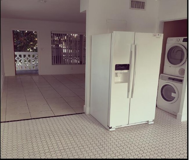 laundry room featuring stacked washer and dryer and tile patterned flooring