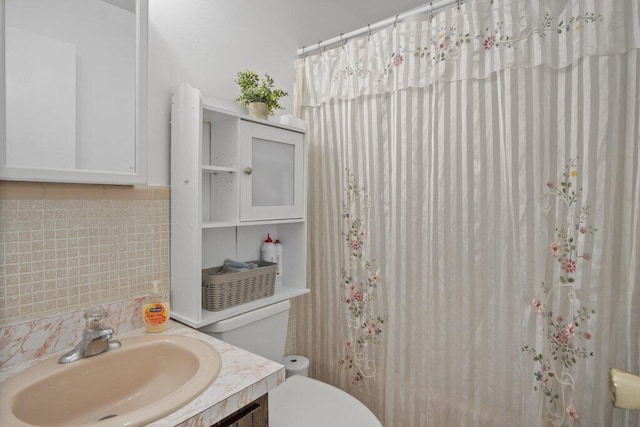 bathroom featuring tasteful backsplash, walk in shower, vanity, and toilet