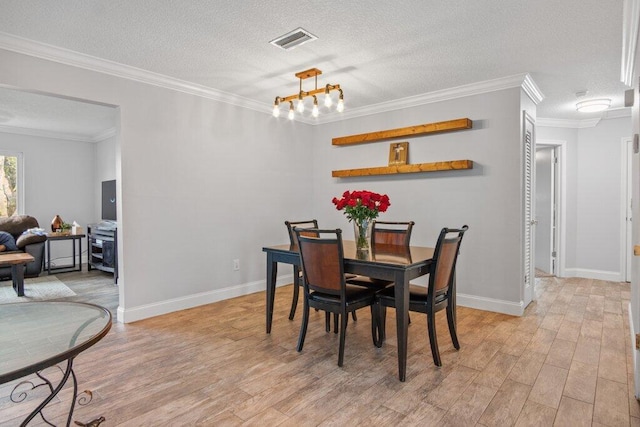 dining room with light hardwood / wood-style floors, crown molding, and a textured ceiling