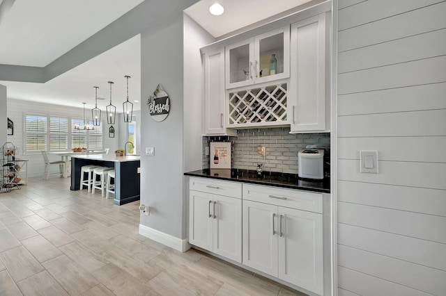 kitchen featuring pendant lighting, a notable chandelier, white cabinetry, and a kitchen breakfast bar