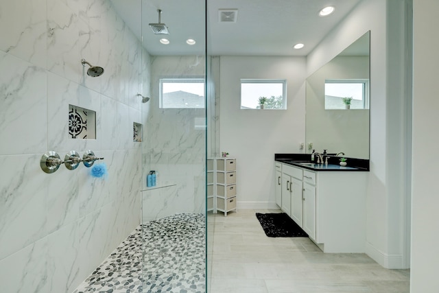 bathroom with a tile shower, vanity, and a wealth of natural light