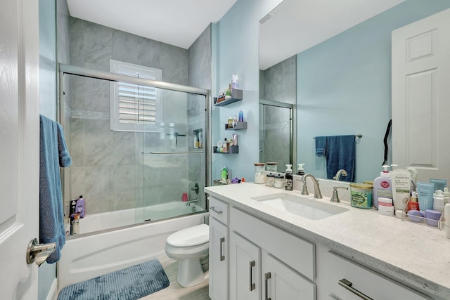 full bathroom featuring bath / shower combo with glass door, vanity, and toilet