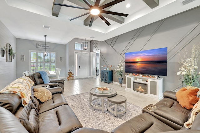 living room with ceiling fan with notable chandelier and light hardwood / wood-style flooring