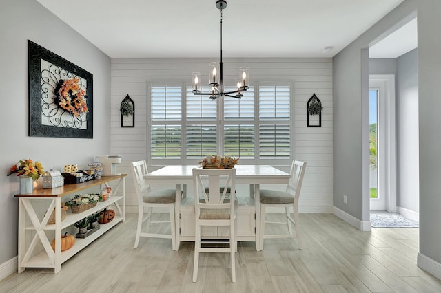 dining room featuring light wood-type flooring, wood walls, and a wealth of natural light