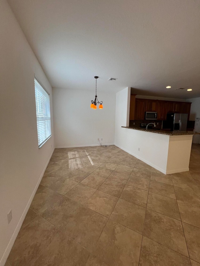 kitchen featuring kitchen peninsula, light tile patterned flooring, decorative light fixtures, a chandelier, and appliances with stainless steel finishes