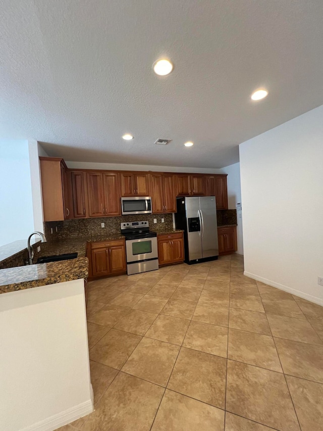 kitchen featuring decorative backsplash, light tile patterned floors, dark stone counters, sink, and stainless steel appliances