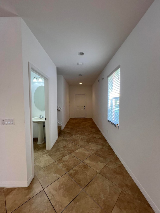 corridor with light tile patterned floors and sink