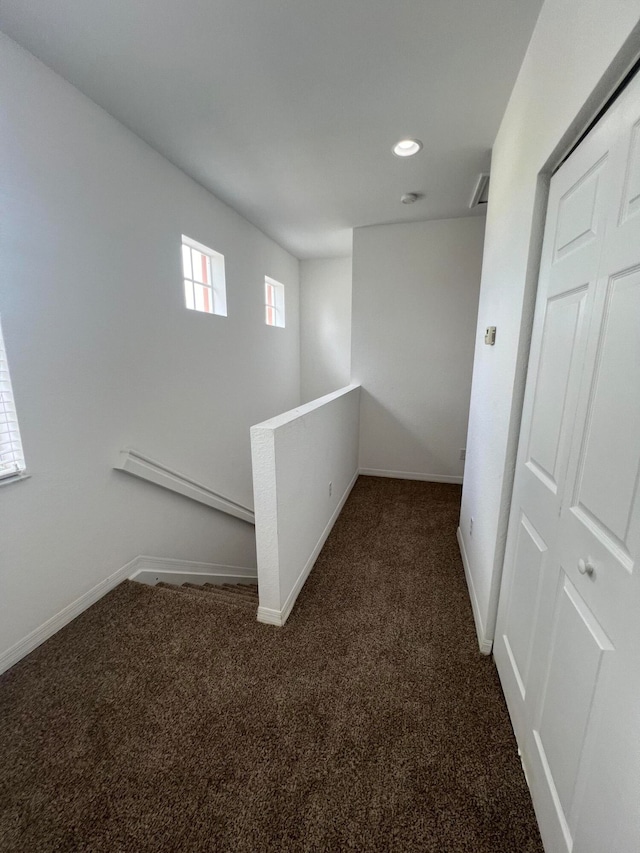 corridor featuring baseboard heating and dark carpet