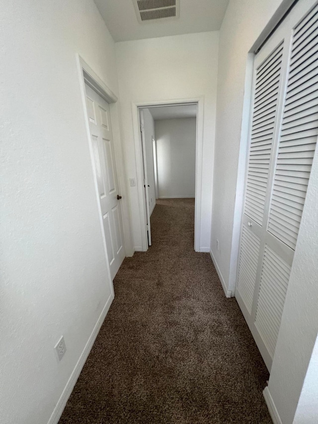 hallway with dark colored carpet