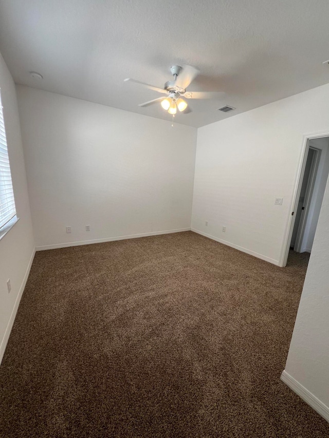 empty room with dark colored carpet and ceiling fan