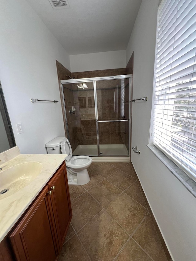 bathroom featuring toilet, a shower with shower door, vanity, and tile patterned floors