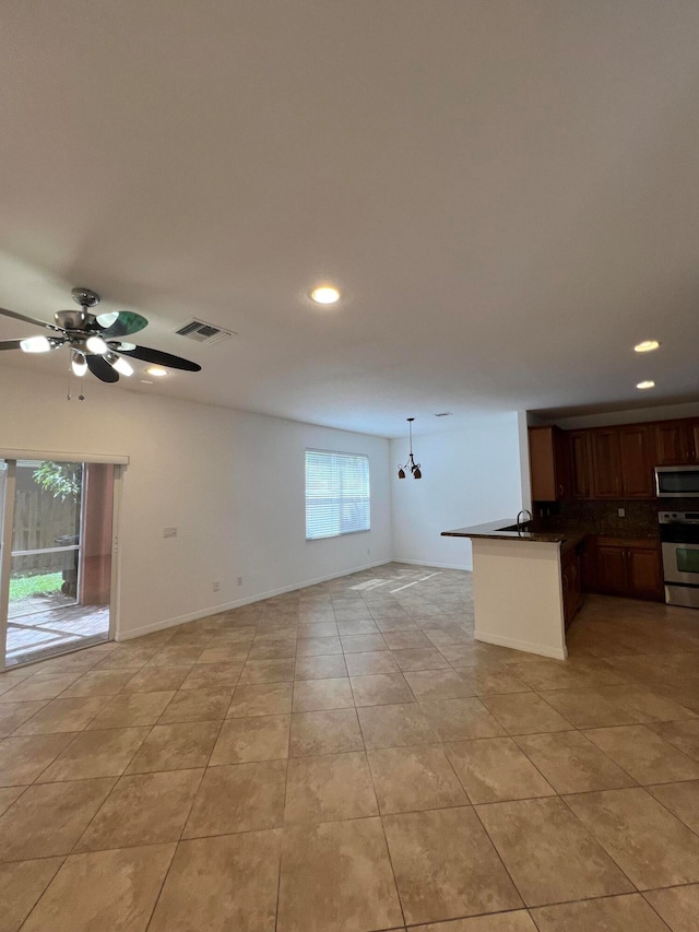 interior space featuring decorative backsplash, kitchen peninsula, pendant lighting, range, and ceiling fan with notable chandelier