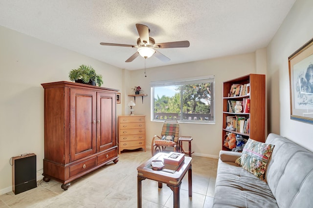 living room with ceiling fan, a textured ceiling, and light tile patterned floors