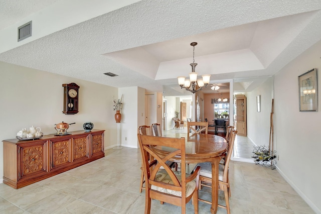 dining room with a textured ceiling, a notable chandelier, and a raised ceiling