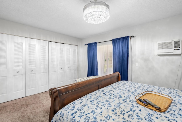 bedroom featuring an inviting chandelier, carpet, a textured ceiling, and a wall mounted AC