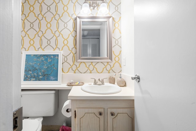 bathroom featuring vanity, toilet, and wallpapered walls