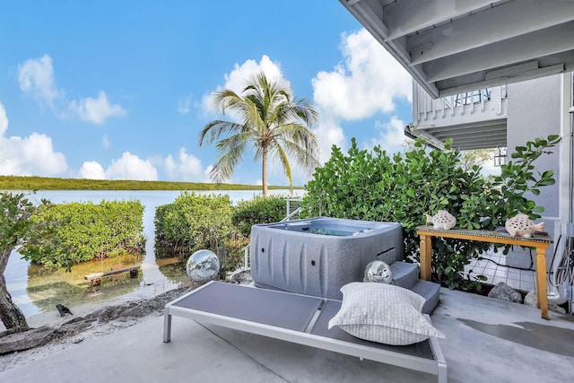 balcony with a hot tub, a water view, and a patio