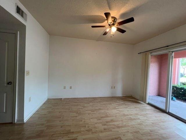 spare room featuring light hardwood / wood-style floors, ceiling fan, and a textured ceiling