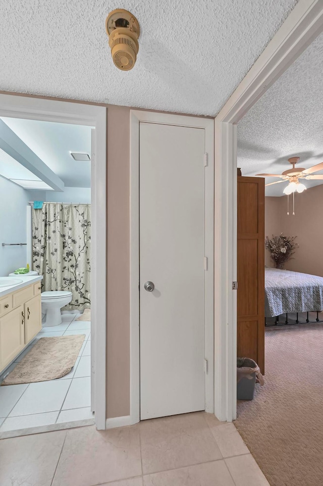 bathroom with a textured ceiling, tile patterned floors, ceiling fan, vanity, and toilet