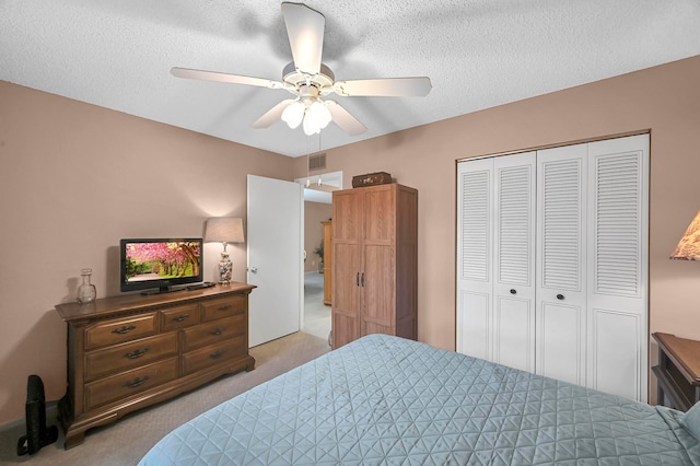 bedroom with a closet, ceiling fan, light colored carpet, and a textured ceiling