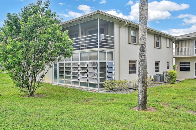 exterior space featuring central AC unit, a sunroom, and a yard