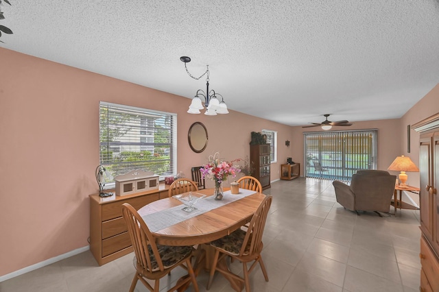 tiled dining room with a textured ceiling and ceiling fan with notable chandelier