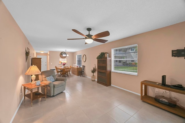 living room with ceiling fan, a textured ceiling, and light tile patterned flooring