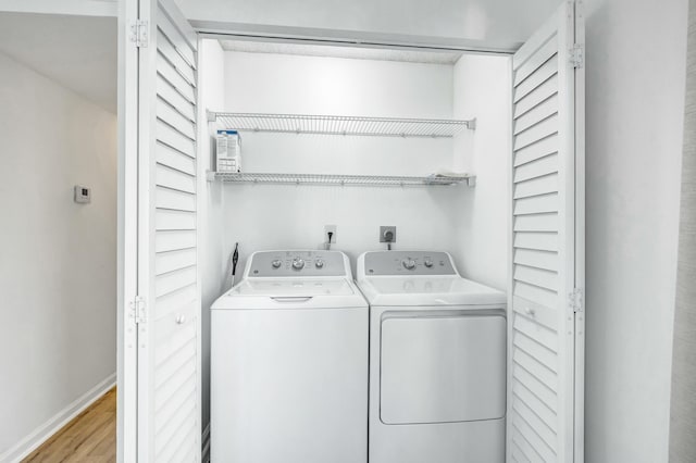 laundry area with washer and dryer and light wood-type flooring