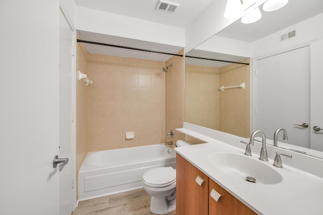 full bathroom featuring hardwood / wood-style floors, vanity, toilet, and tiled shower / bath