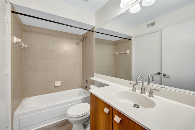 full bathroom featuring vanity, hardwood / wood-style floors, tiled shower / bath combo, and toilet