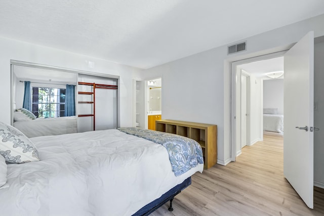 bedroom with ensuite bath and light hardwood / wood-style floors