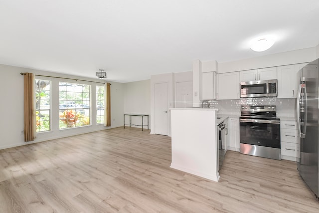 kitchen featuring white cabinets, stainless steel appliances, tasteful backsplash, and light hardwood / wood-style floors