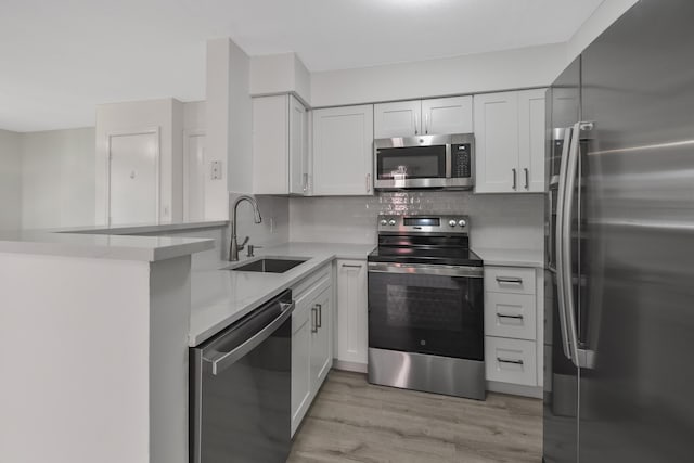 kitchen featuring kitchen peninsula, white cabinetry, sink, and appliances with stainless steel finishes