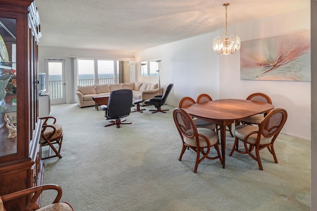 carpeted dining room with a notable chandelier and a textured ceiling