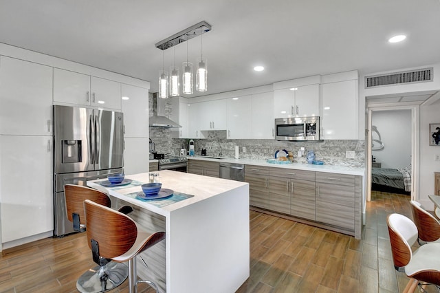 kitchen with light wood-type flooring, sink, white cabinetry, hanging light fixtures, and stainless steel appliances