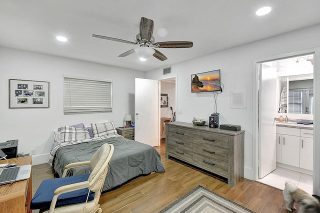 bedroom featuring light wood-type flooring, ensuite bath, and ceiling fan