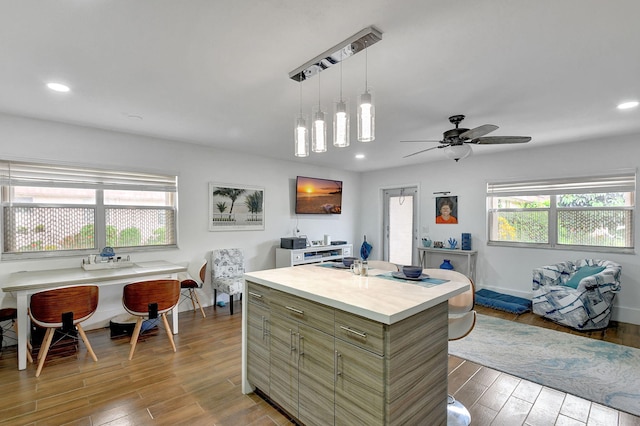 kitchen with hanging light fixtures, a kitchen island, hardwood / wood-style floors, and ceiling fan