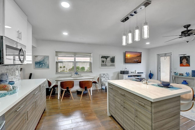 kitchen featuring ceiling fan, white cabinets, hanging light fixtures, a kitchen island, and dark hardwood / wood-style floors