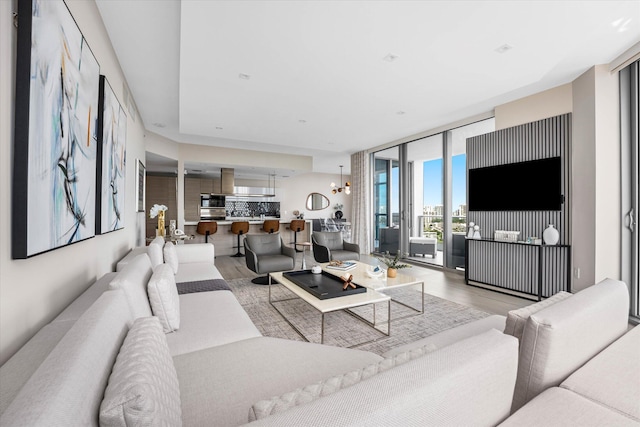 living room featuring light wood-type flooring, a chandelier, and expansive windows