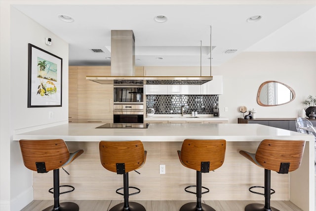 kitchen featuring a kitchen breakfast bar, decorative backsplash, a center island, and stainless steel double oven