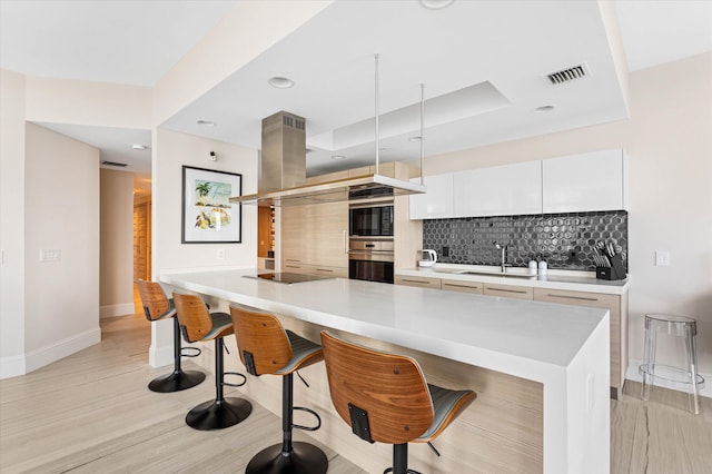 kitchen with a kitchen breakfast bar, white cabinets, tasteful backsplash, and sink