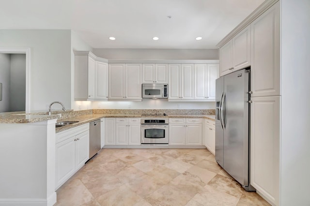 kitchen with light stone counters, stainless steel appliances, sink, and white cabinetry