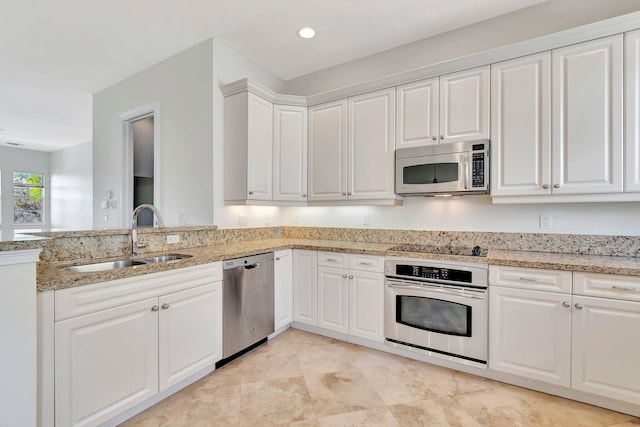 kitchen featuring stainless steel appliances, white cabinets, light stone counters, and sink