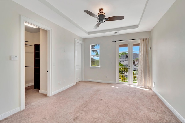 carpeted spare room with ceiling fan and a raised ceiling