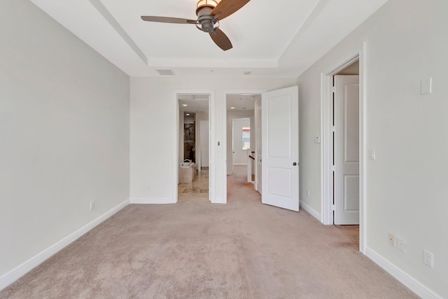 unfurnished bedroom with a raised ceiling, ceiling fan, and light colored carpet