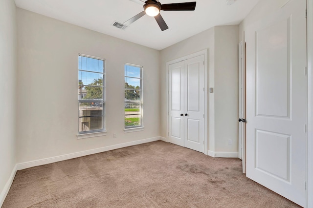 unfurnished bedroom with light carpet, ceiling fan, and a closet